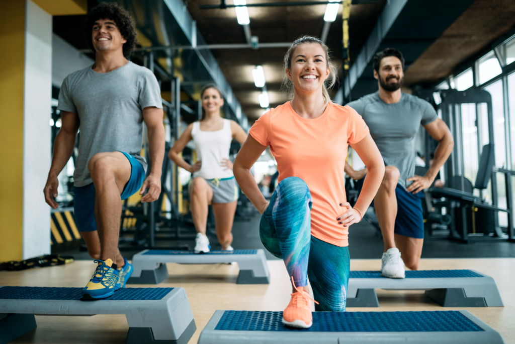 Vier Personen machen im Fitnessstudio Sportübungen.