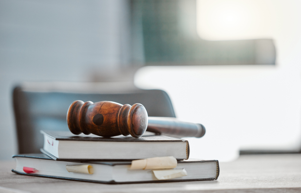 Gerechtigkeit, Hammer und Gesetzbücher auf einem Tisch im Büro für Gerichtsverhandlung, Gesetzgebung oder faire Verfassung im Justizsystem. Kanzlei, Nahaufnahme und Richterhammer mit Unterlagen für einen Unternehmensfall am Arbeitsplatz.